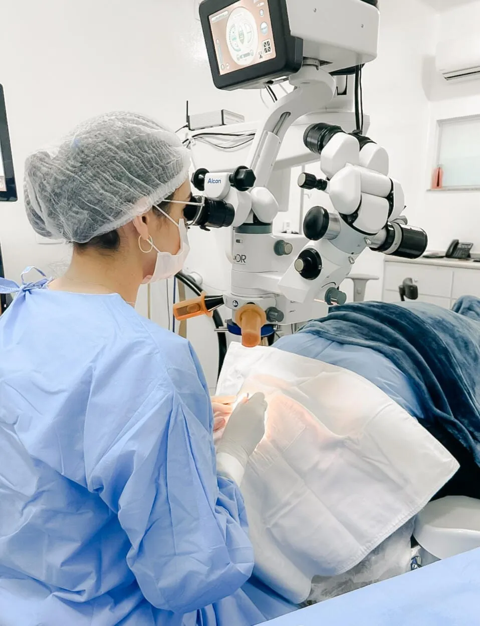 Dra. Bruna Pevide operando ao microscópio no centro cirúrgico